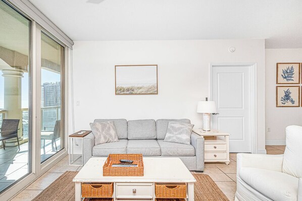 Un salon moderne avec un canapé, une table basse et une vue à travers une porte vitrée.
