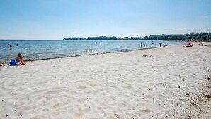 A beach with people swimming and walking along the shore.