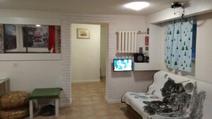 A living room with a white sofa, a green stool, a TV, and a radiator. - APARTAMENT W CENTRUM NOCLEGI PŁOCK (Plock)