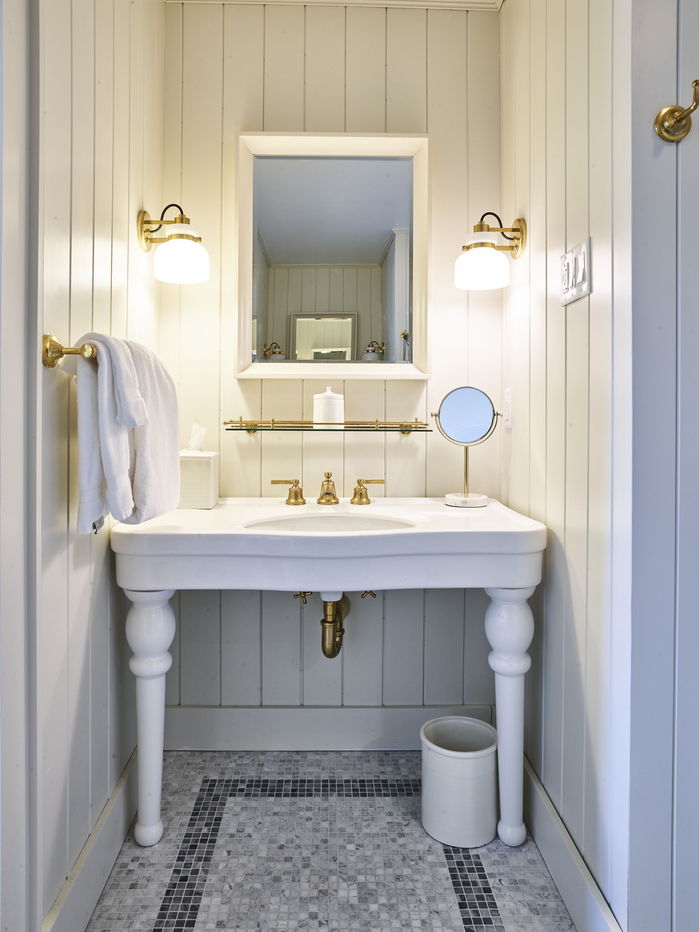 A bathroom with a white sink, gold fixtures, and a mirror.