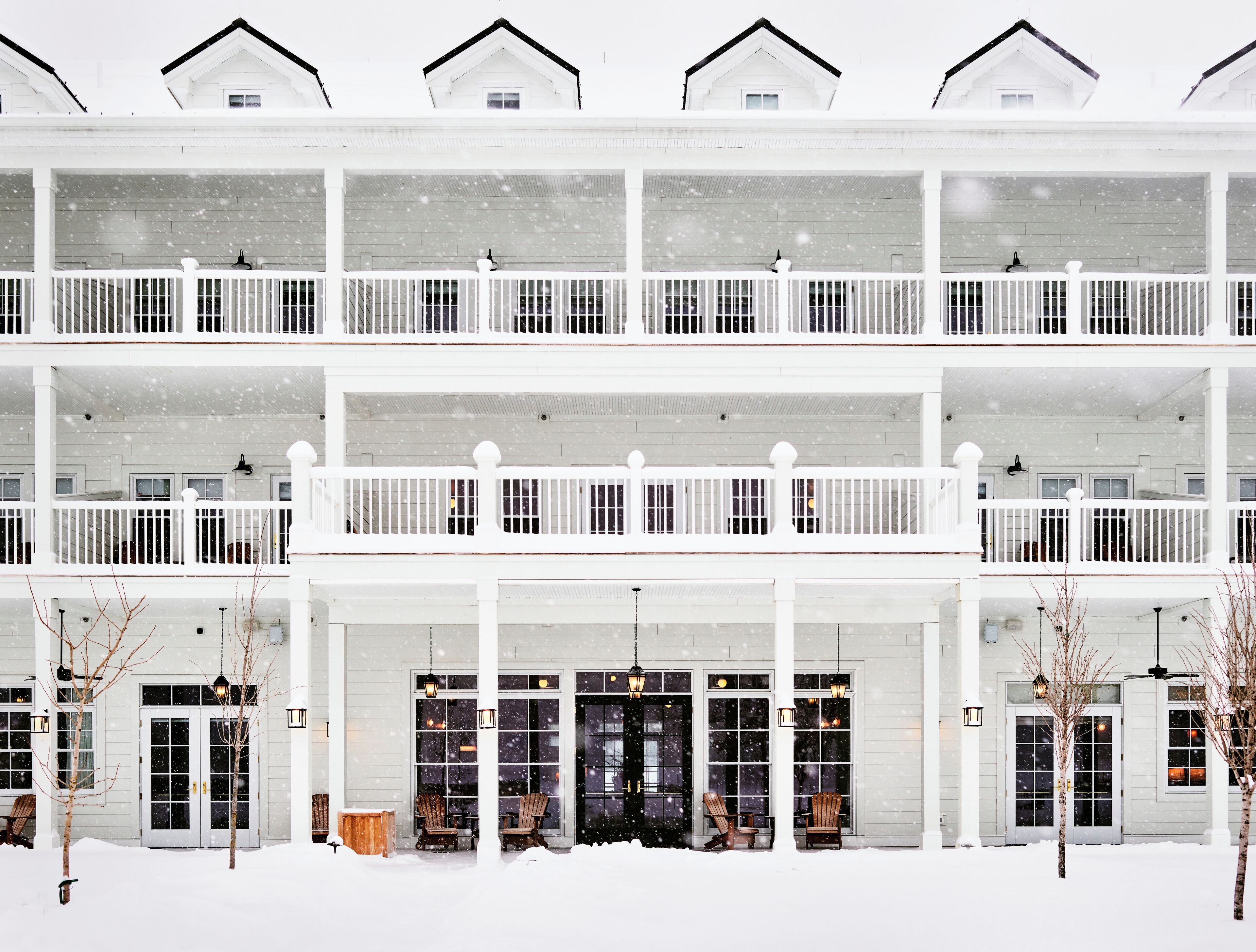 Un immeuble à plusieurs étages, à la façade blanche, doté de nombreux balcons et d’un porche avant couvert avec des sièges.