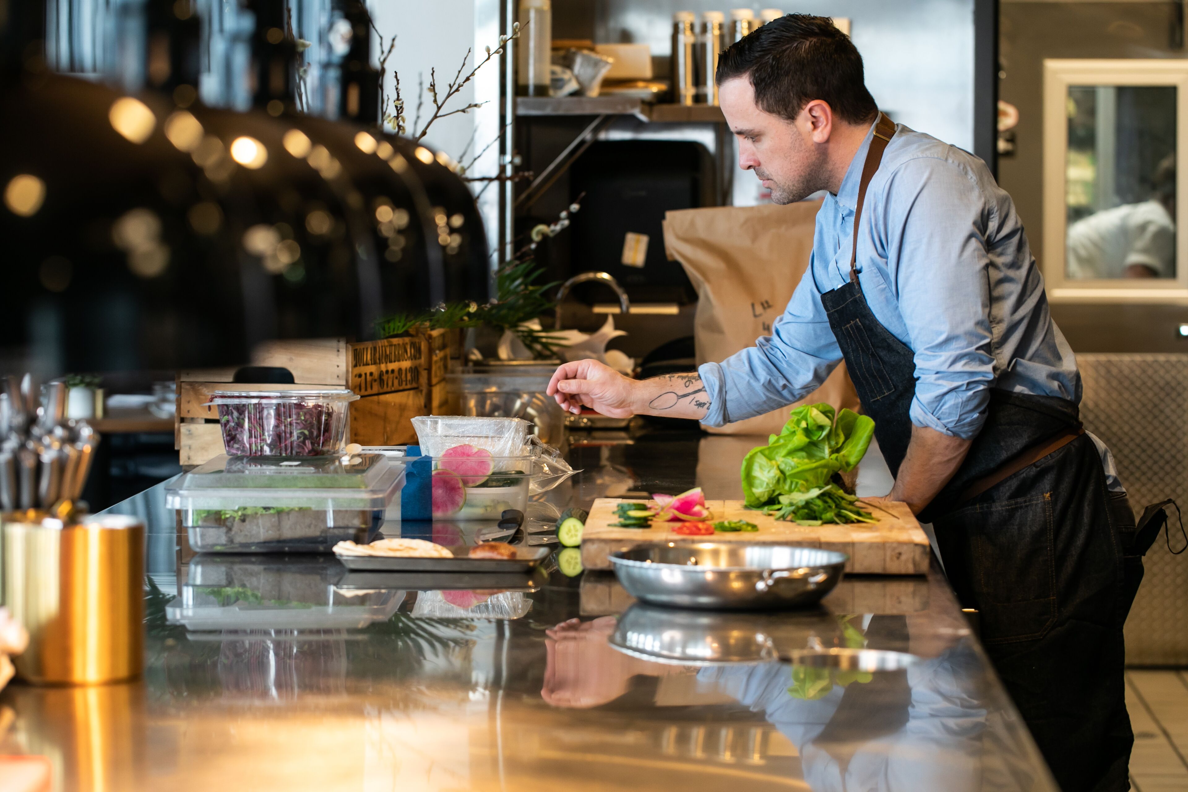 A chef preparing food at a counter with various ingredients and kitchen tools.