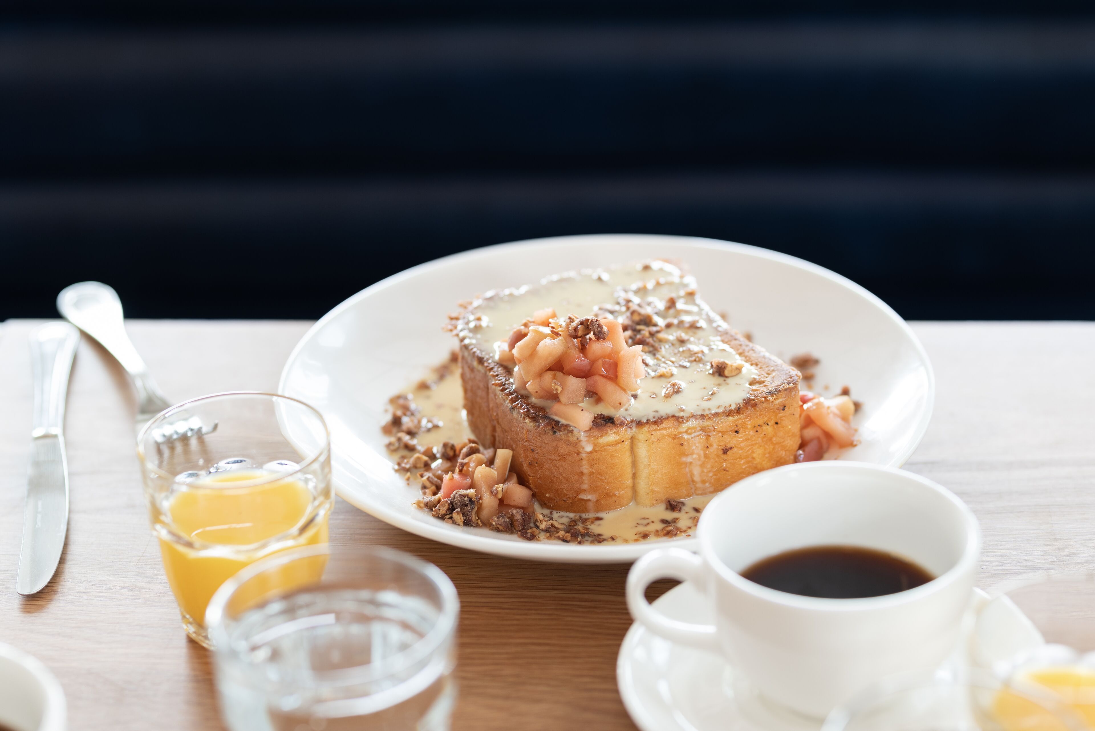 A breakfast setting with toast, fruit, and coffee on a wooden table.