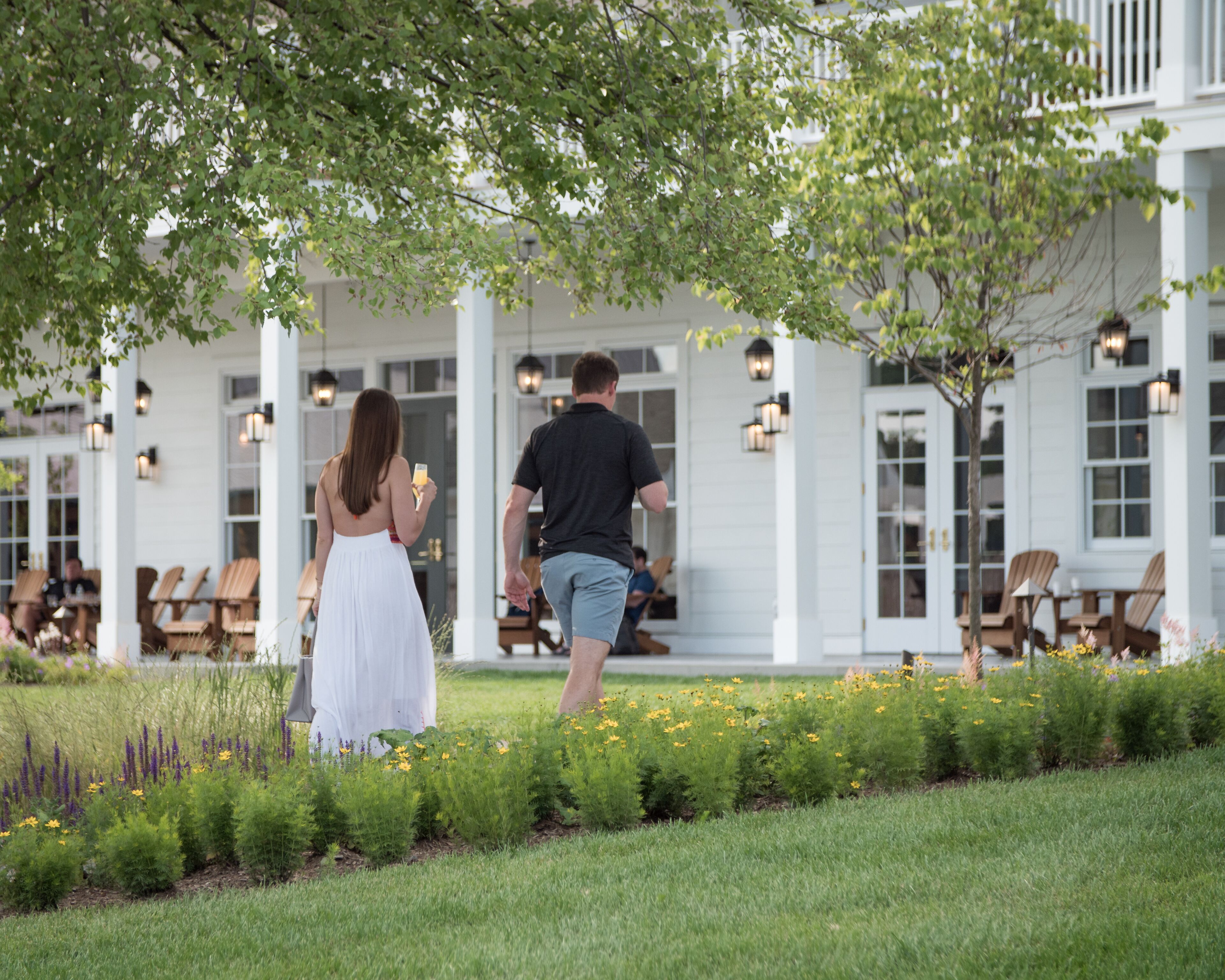 A couple walking on a porch with a garden in the foreground.