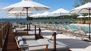 A poolside area with lounge chairs and umbrellas, overlooking a body of water.