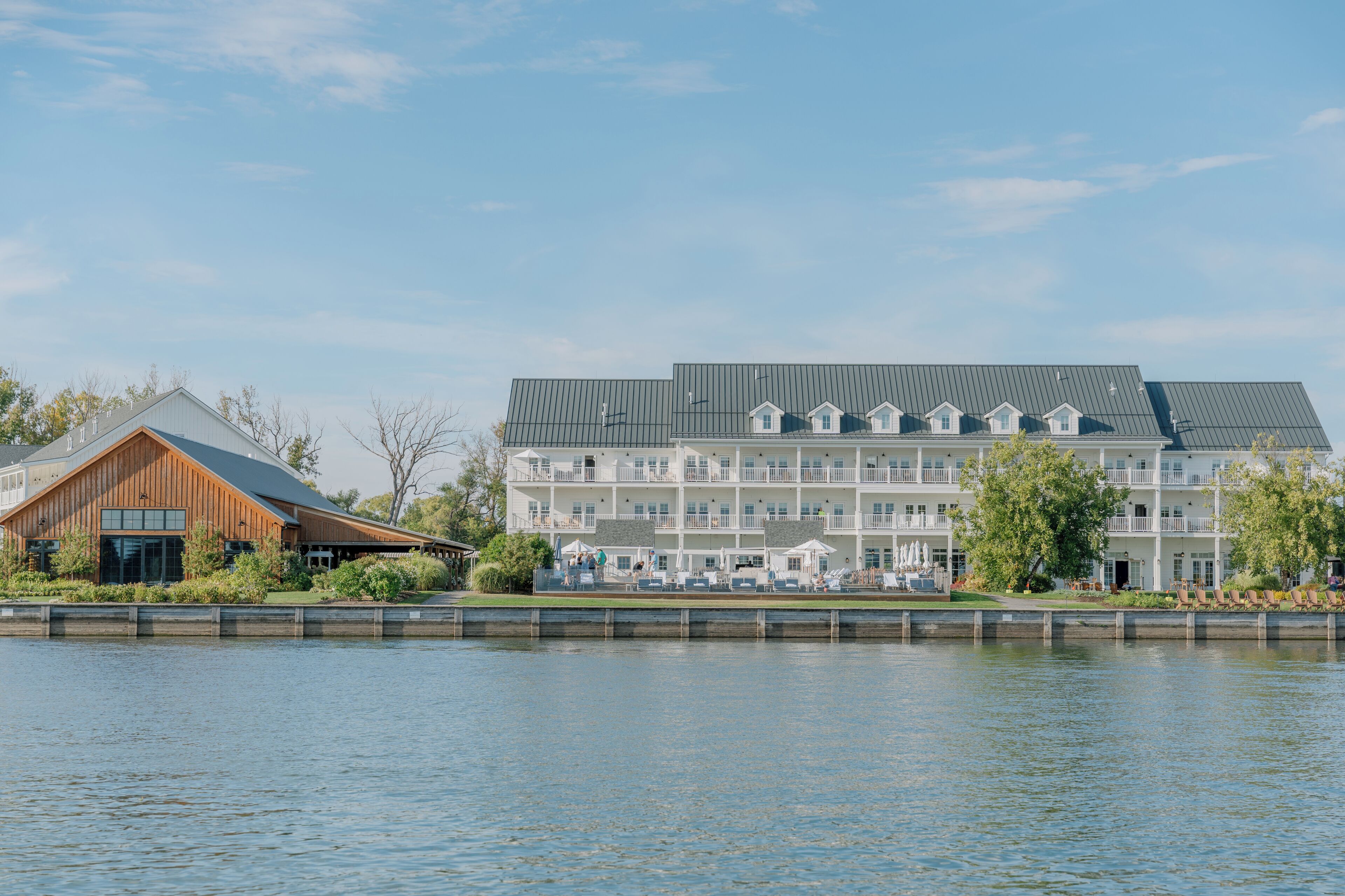 A waterfront hotel with a large building, a smaller structure, and a dock.
