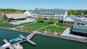 A resort with a swimming pool, outdoor seating, and a dock with boats.
