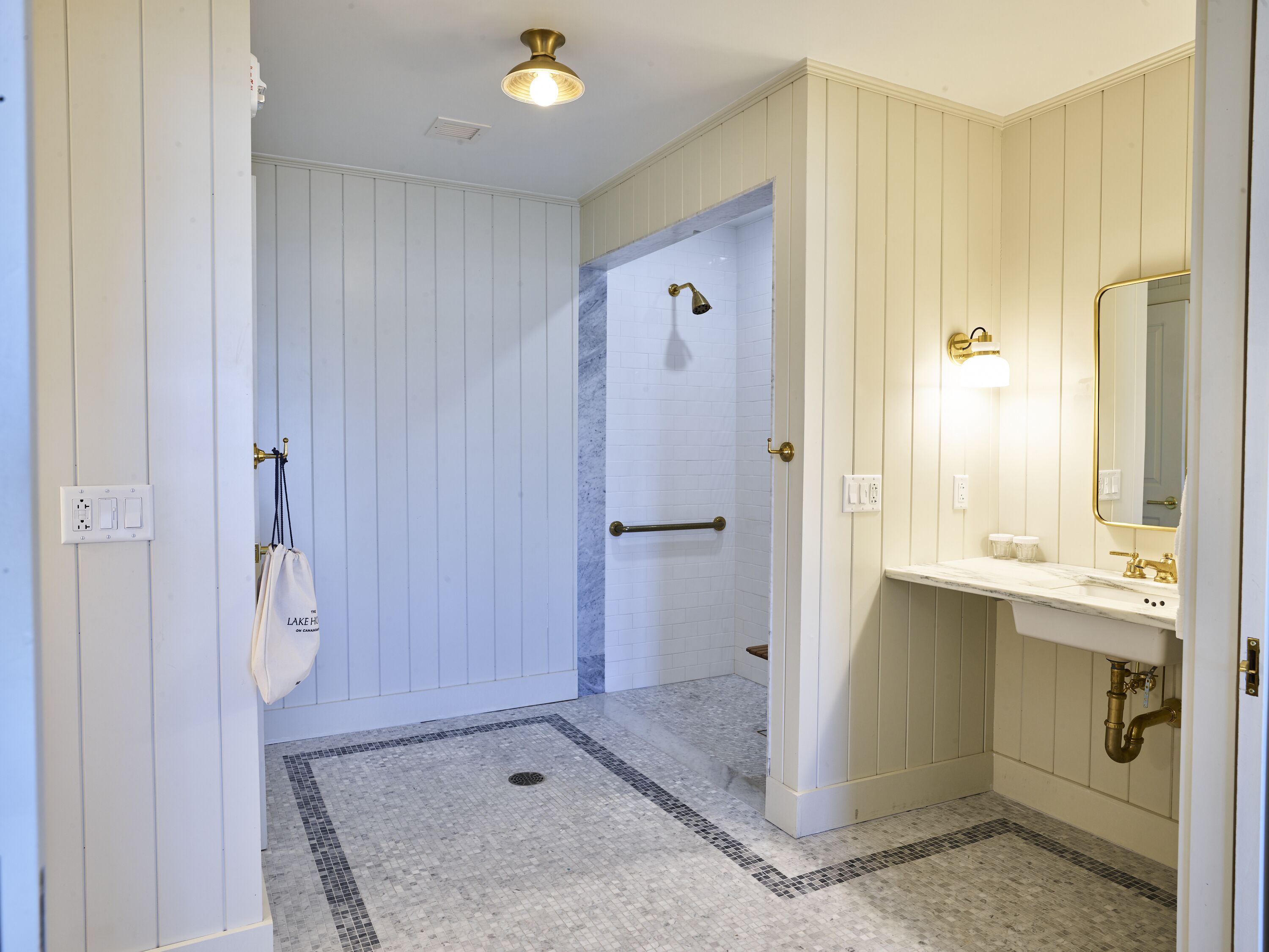 Ein Badezimmer mit Dusche, Waschbecken mit Spiegel und einem Handtuch an der Wand.