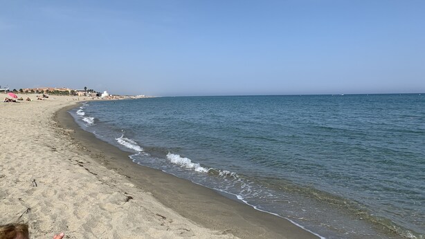 Ein Strand mit sandigem Ufer und ruhigem Meer.
