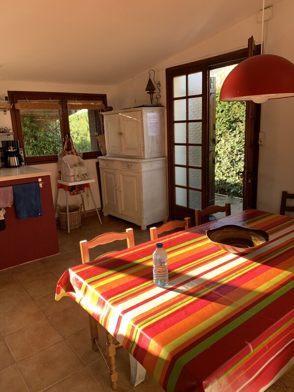 Un coin repas avec une table recouverte d’une nappe à rayures, des chaises et une bouteille d’eau posée sur la table.