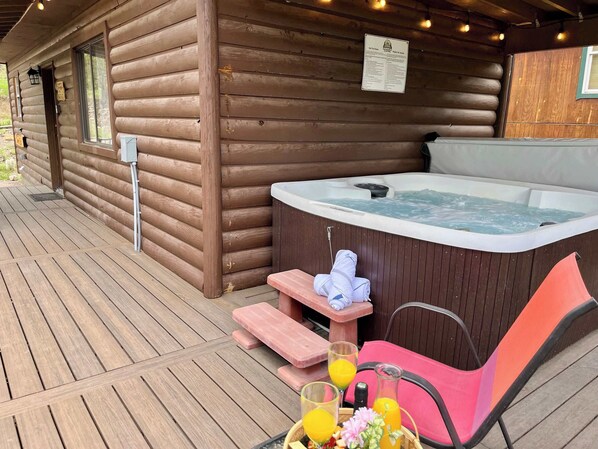 A wooden cabin with a hot tub, outdoor seating, and a wooden deck. - Pet-Friendly Sleepin Inn Cabin w/ Hot Tub & Fireplace (Ruidoso)