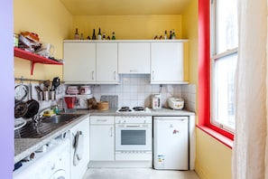 Compact kitchen with a stove, sink, refrigerator, and ample storage.