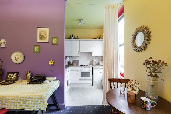 Efficient kitchen with stove, oven, and refrigerator, adjacent to a dining area with a table and chairs.