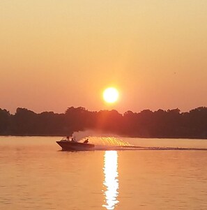 Un bateau sur une étendue d’eau calme, au coucher du soleil.