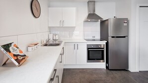 Una cocina moderna con armarios blancos, un refrigerador de acero inoxidable, un horno y un lavamanos.