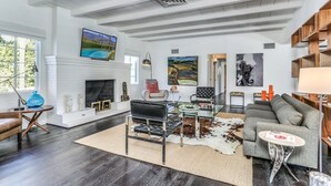 Un salón amplio con chimenea, un sofá grande, una mesa de centro y un tapiz de cuero de vaca.