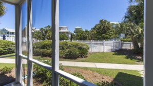 A view through a window of a residential area with a white picket fence, well-maintained lawns, and houses in the background. - Deeded Beach Access, Community Pool, Screen Porch, Walk to Shops and Restaurants (Santa Rosa Beach)