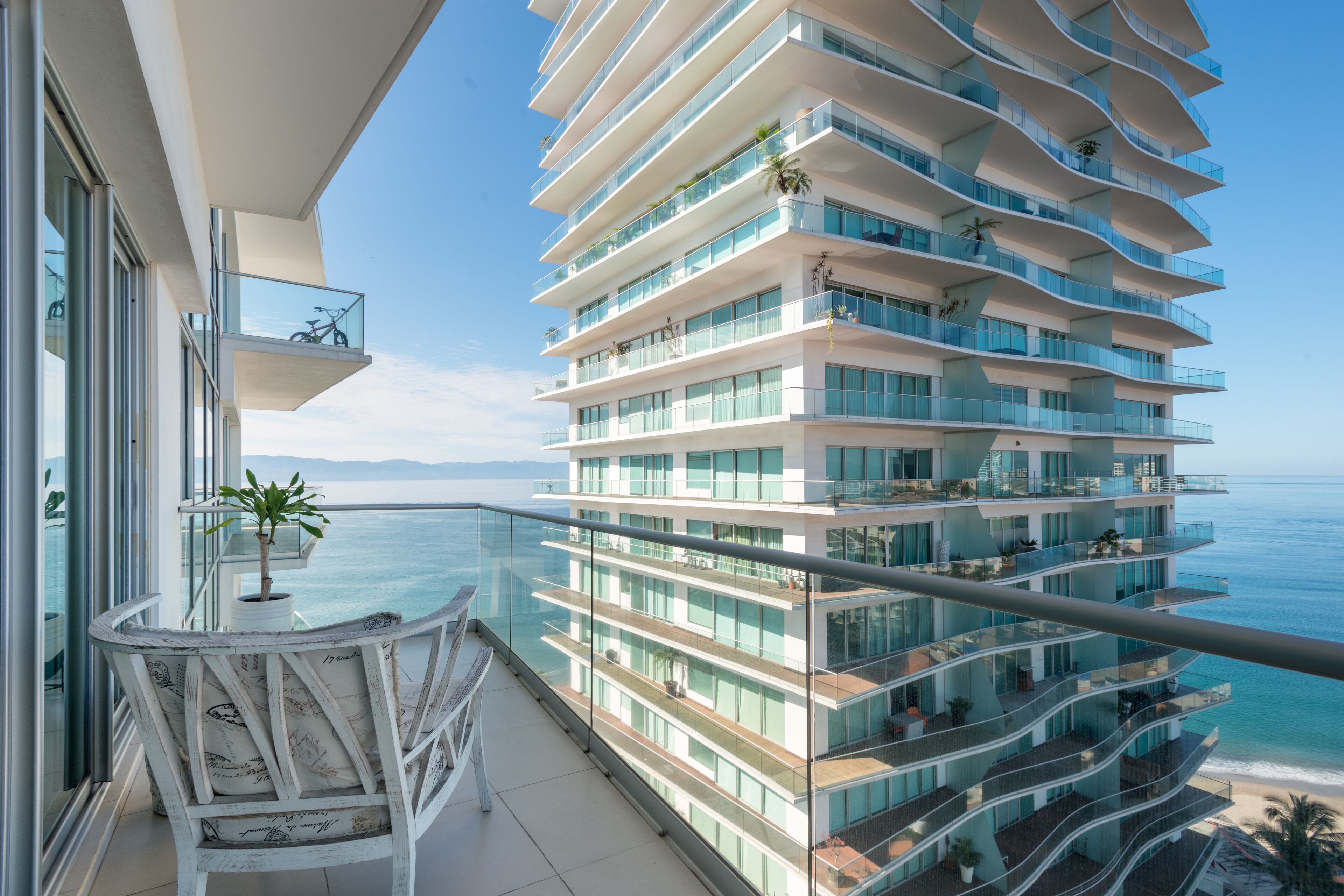 Un immeuble moderne à plusieurs étages, doté de balcons donnant sur une plage.