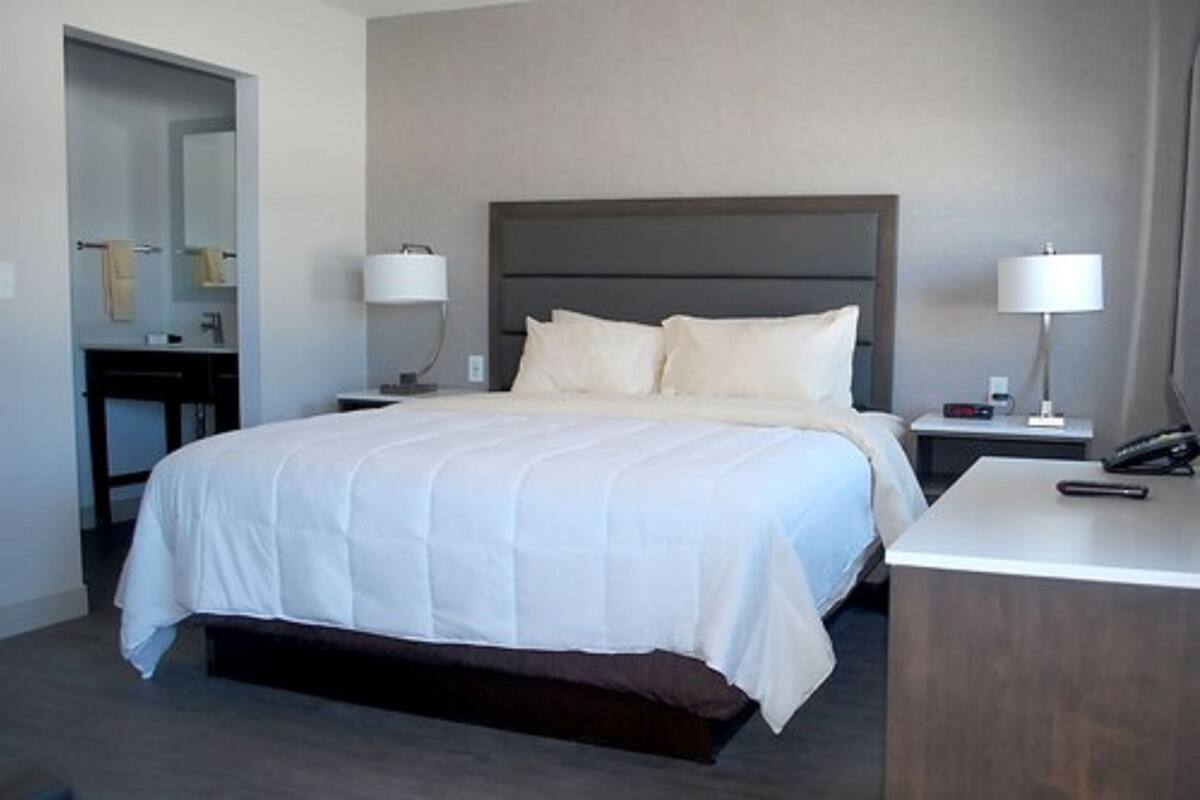 A hotel room with a large bed, bedside tables, a desk, and a mirror.