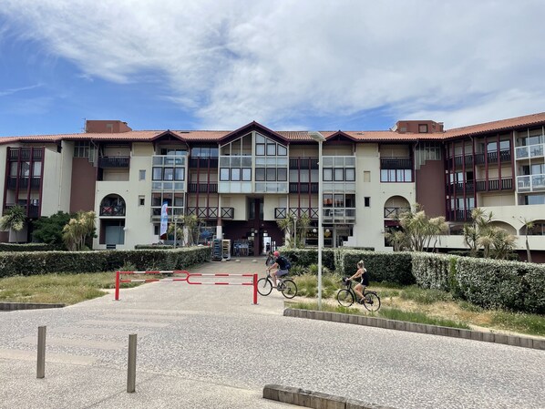 A multi-story building with a central entrance, balconies, and a gated driveway. - Apartment T3 with terrace, 100 m from the beach and 5 min by bike from the lake (Soorts-Hossegor)