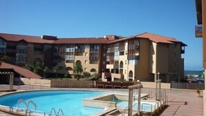 A hotel with a swimming pool, multiple balconies, and a view of the sea. - Apartment T3 with terrace, 100 m from the beach and 5 min by bike from the lake (Soorts-Hossegor)