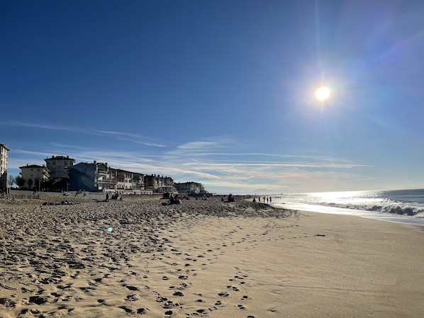 Una playa con edificios al fondo y huellas en la arena.
