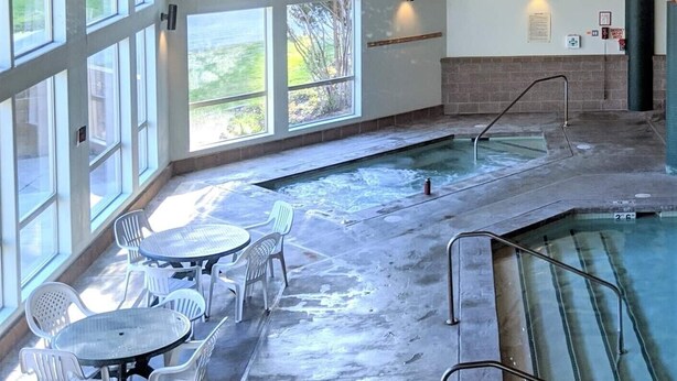 Un espace spa comprenant un bain à remous, des sièges et de grandes fenêtres.