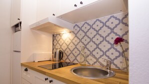 A compact kitchen with a wooden countertop, stainless steel sink, and a patterned backsplash. - Casa Alameda Cadiz Centro (Cádiz)