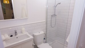 A modern bathroom with a white sink, toilet, and glass-enclosed shower. - Casa Alameda Cadiz Centro (Cádiz)