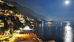 A coastal town at night with illuminated buildings, a beach, and boats on the water.