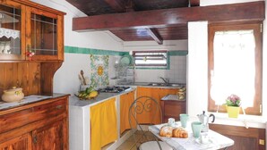 A kitchen with wooden cabinets, a stove, a sink, and a dining area with a table and chairs.