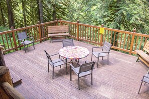 A wooden deck with a round table and chairs, surrounded by a wooden railing. - Escape to Magical "Minikahda Lodge" on Clear Creek in Rhododendron (Rhododendron)