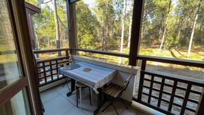 A small balcony with a table and chairs, overlooking a forested area. - 132 - Apartment 5 minutes from the ocean (MAUBUISSON)