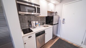 A compact kitchen with white cabinets, a stainless steel microwave, a black refrigerator, and a dishwasher. - Slopeside 2762 (Keystone)
