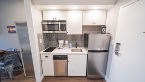 A compact kitchen with white cabinets, a stainless steel refrigerator, a microwave, and a dishwasher. - Slopeside 2762 (Keystone)