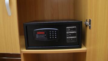 A black safe with a keypad and instructions on a wooden shelf.