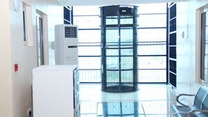 Un vestíbulo con puerta giratoria, un equipo de aire acondicionado blanco y un banco.
