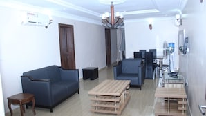 Una sala moderna con un sofá azul, una mesa de centro de madera y una mesa de comedor de vidrio.