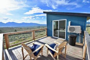 A deck with two chairs and a table, overlooking a mountainous landscape. - Modern Tiny House with Spectacular Views (Stevensville)