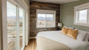 Quarto com uma cama grande, janela com vista para as montanhas e parede de madeira.