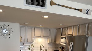 A modern kitchen with granite countertops, stainless steel appliances, and white cabinetry. - Stunning Royal Garden Unit 1002 (Murrells Inlet)