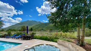 A hot tub surrounded by a pool, lounge chairs, and a table with an umbrella. - Red Hawk Lodge 2241 OFB (Keystone)
