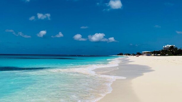Ein Strand mit klarem türkisblauem Wasser und weißem Sand.