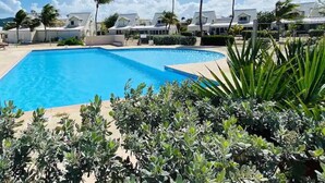 Ein Swimmingpool, umgeben von Palmen und weißen Gebäuden.
