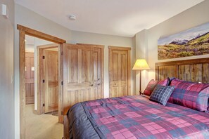 Un dormitorio con una cama grande, un armario de madera y un cuadro en la pared.