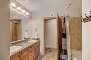Un baño con dos lavamanos, un espejo grande y una zona de ducha.