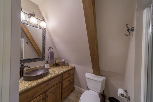 A bathroom with a wooden vanity, a large mirror, and a white toilet. - Fly-In Home on Monkey Island, Grand Lake OK (Afton)