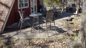 Ein rotes A-Haus mit einer Terrasse, die Sitzgelegenheiten und einen Kamin aus Stein bietet.
