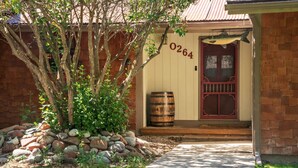 A house with a red door, number 0264, a wooden barrel, and a stone pathway leading to the entrance.