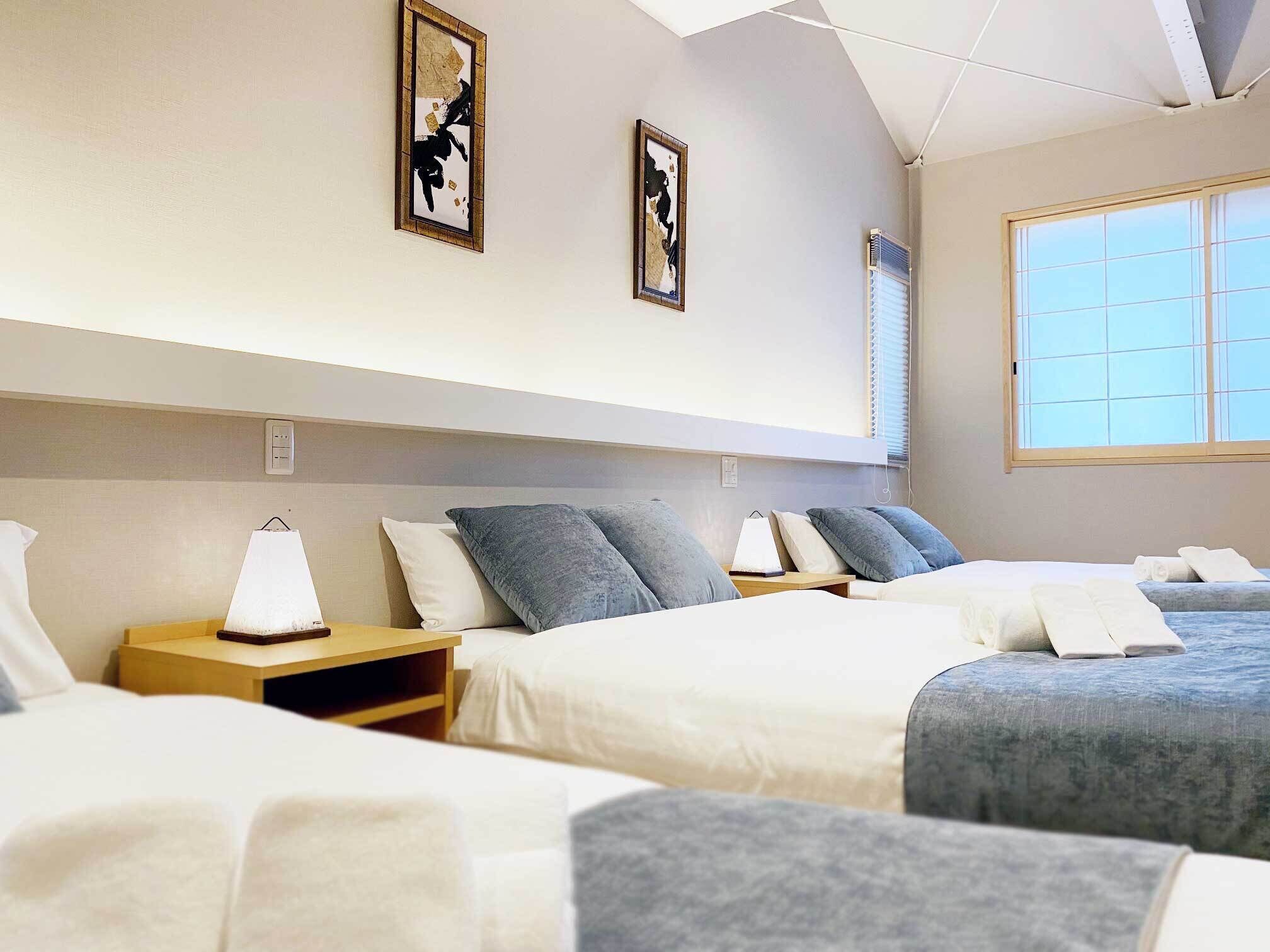 A hotel room with two beds, a large window, and artwork on the walls.